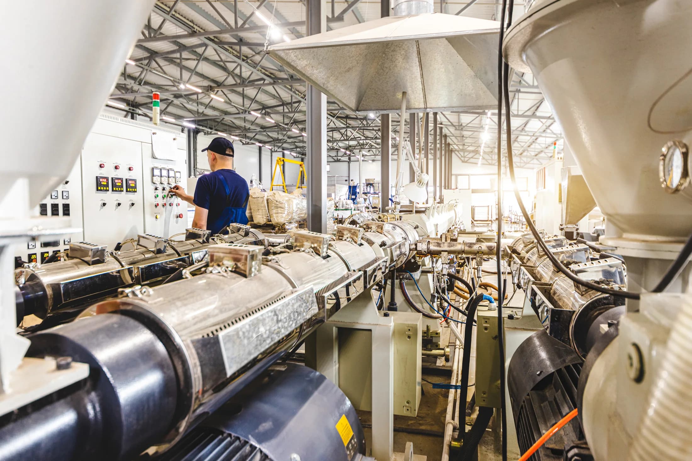 A technician working among plastic extrusion lines on the production floor